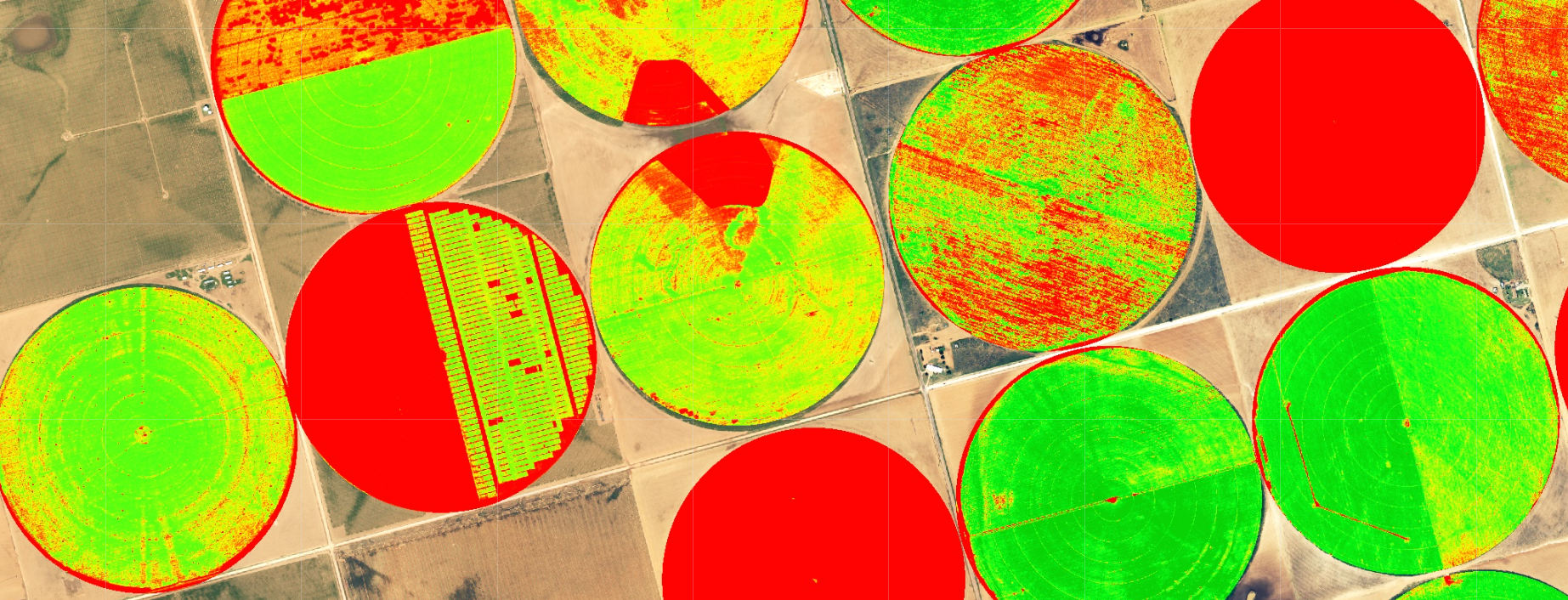 This image shows a natural color composite satellite image of a field containing irrigation center pivots in which the boundary within the pivot is being presented as a vegetation index NDVI in false color composite from red for areas with little vegetation to green for areas with lots of vegetation.